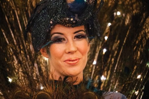 A world class roving performer with peacock styled headpiece and feather costume for a private party