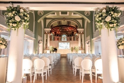 Hanging florals with white hydrangeas and foliage at One Marylebone in London with white chandelle chairs set in a ceremony configuration and white hydrangea flower arrangements at One Marylebone for a private elegant event