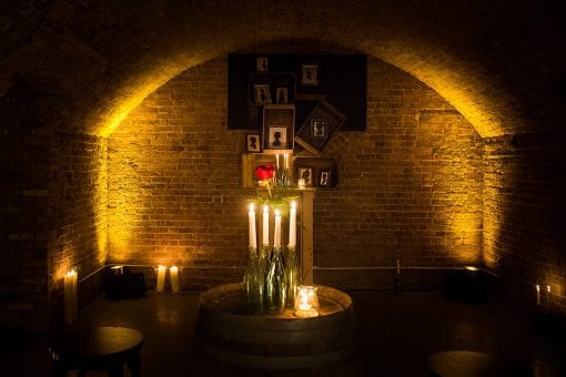 Candle lit underground room with picture frames on the wall for a private event
