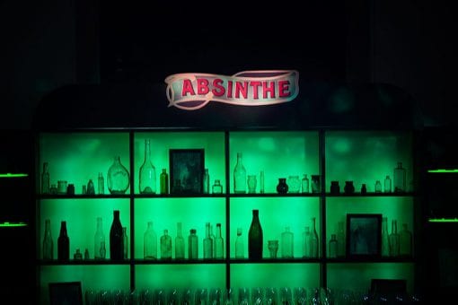 A bespoke Absinthe bar lit with green lighting for a Moulin Rouge party