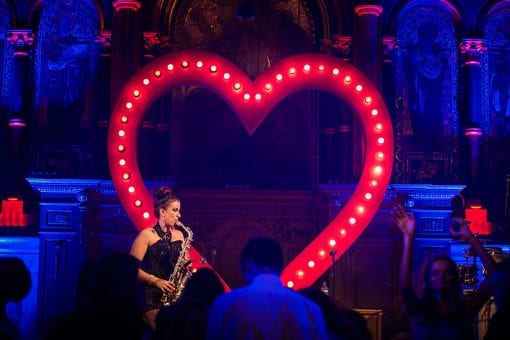 Female sax player performing by an illuminated red heart for a fun event in London
